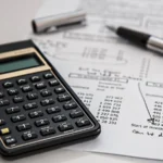Calculator on financial documents representing logo design cost across pricing tiers in 2026
