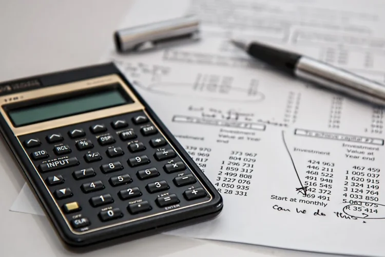 Calculator on financial documents representing logo design cost across pricing tiers in 2026