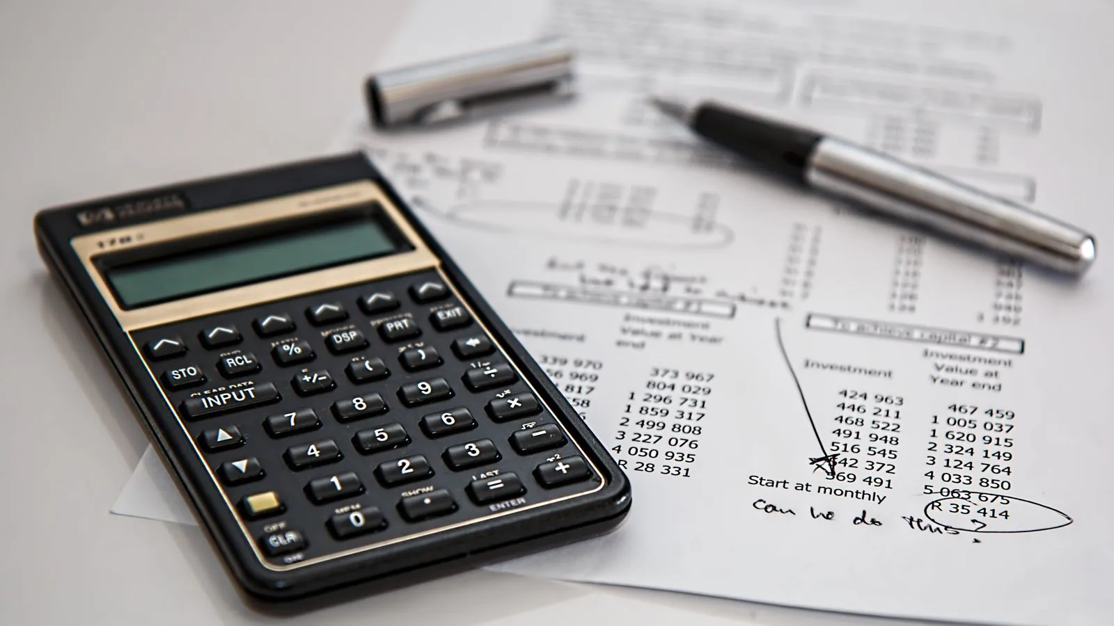 Calculator on financial documents representing logo design cost across pricing tiers in 2026