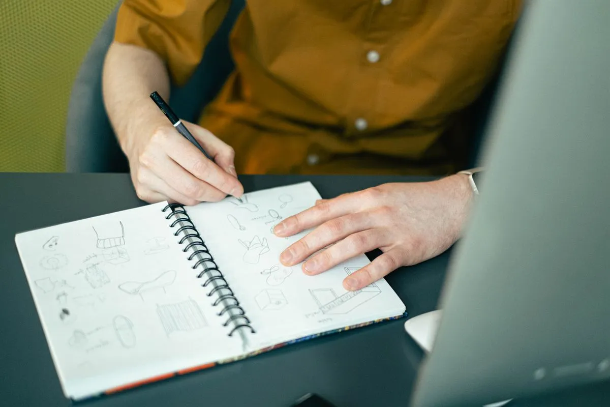 Designer sketching logo design ideas in a notebook at a desk