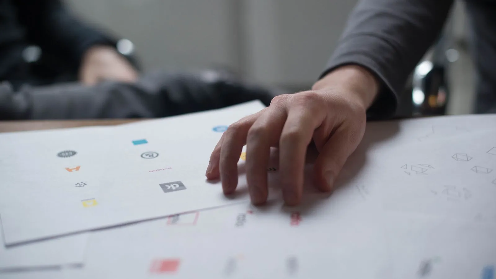 Hand reviewing different types of logos printed on paper